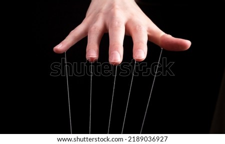 Hand manipulating and controlling smth with strings concept. High quality photo