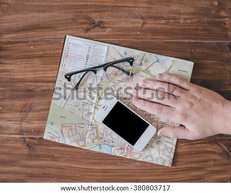 Hand, map, glasses and phone on the wood table