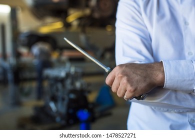 Hand master inspector in the service station in a white shirt with a screwdriver. The process of work in the service station, the master on the background of the repair area. - Shutterstock ID 1478527271