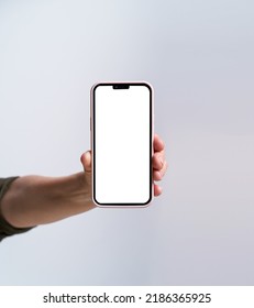 Hand Of Mature Woman Holding Smartphone With White Screen Isolated On White Background. Modern Phone With Touch Screen In Woman Hand. Close Up. Mock Up Mobile App Advertising. No Face Visible.