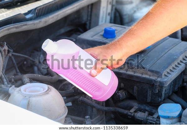 Hand of mechanic\
filling in cooling liquid