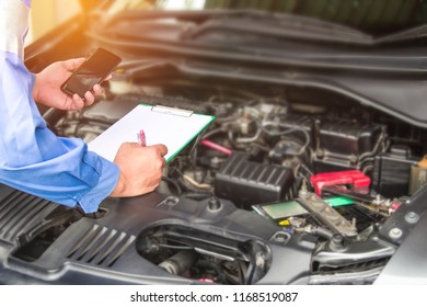 Hand Mechanic Hold Check Sheet Paper And Smart Phone For Basic Checking A Engine Of Car,maintenance And Service Check In Garage