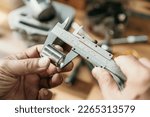 Hand of mechanic holding Vernier Caliper Measurements on a steel Shaft Bush or motorcycle part at motorcycle shop , selective focus, 