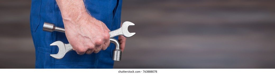 Hand of mechanic holding wrenches on blurred background - Shutterstock ID 763888078