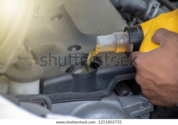 hand\
mechanic pouring motor oil to motor  car,\
closeup