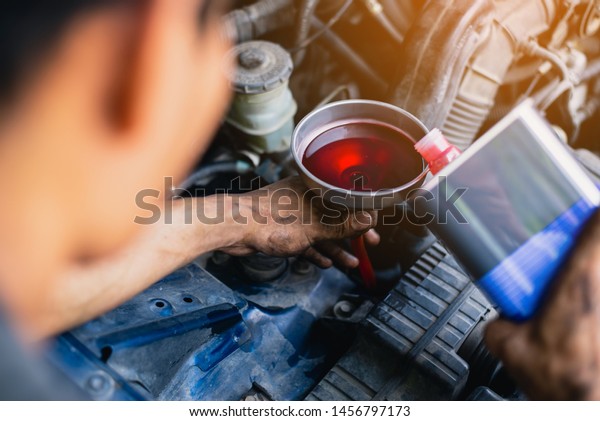 Hand mechanic in repairing car , Gear oil change,\
Filling the oil through the hose. Car maintenance station. Red gear\
oil.