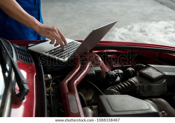 Hand of mechanic using laptop computer checking\
car at garage.
