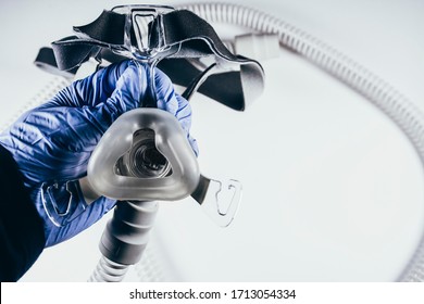 Hand With Medical Glove Holding Respiratory Mask For Sleep Disorders Isolated. White Background. Apnea. Medical Devices. Air Pump. Assisted Breathing