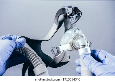 Hand With Medical Glove Holding Respiratory Mask For Sleep Disorders Isolated. White Background. Apnea. Medical Devices. Air Pump. Assisted Breathing