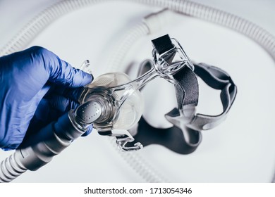 Hand With Medical Glove Holding Respiratory Mask For Sleep Disorders Isolated. White Background. Apnea. Medical Devices. Air Pump. Assisted Breathing