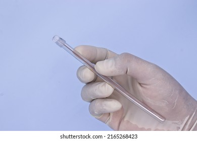 Hand With Medical Glove Holding Saliva Suction Tube On Blue Background