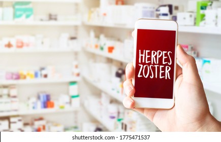 Hand in medical glove holding smartphone on white background. Blank screen with herpes zoster text.