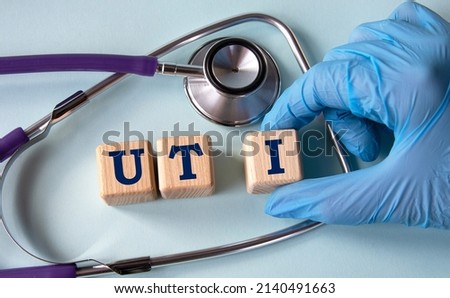 A hand in a medical glove puts cubes with the abbreviation UTI (Urinary Tract Infection) on the background of a stethoscope. Medical concept Stock foto © 