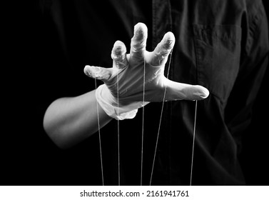 Hand in medical glove with strings on fingers. Deception in medicine and pharmacy, conspiracy theory, health care fraud, control and power over patient concept. Black and white. High quality photo