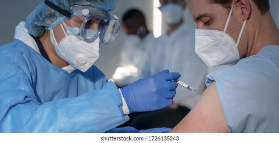 Hand des medizinischen Personals, das den Impfstoff Coronavirus covid-19 in einer Impfspritze injiziert, um den Muskel des Kaukasiers für die Impfung gegen Coronavirus covid-19, die Impfung gegen Coronavirus covid-19, die Impfung gegen Coronavirus covid-19, die selektive Fokussierung