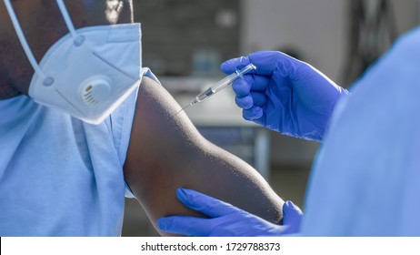 Hand des medizinischen Personals, das den Impfstoff Coronavirus covid-19 in einer Impfspritze injiziert, um den Muskel des afrikanischen Amerikaners für die Impfung gegen Coronavirus covid-19 zu bewaffnen