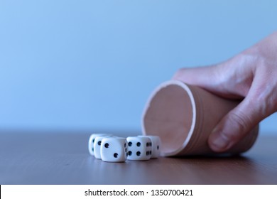 Hand Of A Men Playing Yahtzee With Brown Leather Cup And Dices