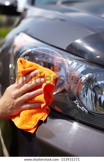 Hand with microfiber\
cloth cleaning car.