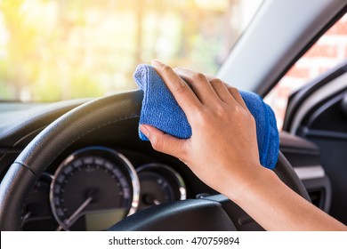 Hand with microfiber cloth cleaning Interior and steering wheel modern car.