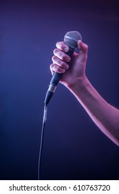 Hand With Microphone On A Black Background, The Music Concept, Beautiful Lighting On The Stage, Closeup