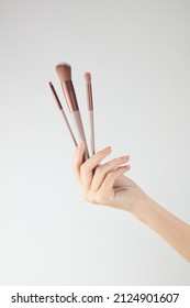 Hand Model Holding A A Set Of Makeup Brushes With A White Background For Cosmetic Advertising