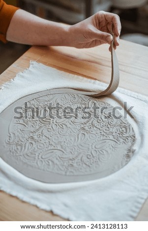 Hand modelling of openwork clay plate, pottery. Women's hands working with clay, close-up