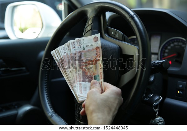 Hand with money. Banknotes five\
thousand Russian rubles in the hand on the steering wheel of a car.\
Cash paper money. Five thousandth bill. Auto\
industry.