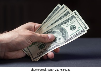 Hand with money on dark background - Shutterstock ID 2177554983