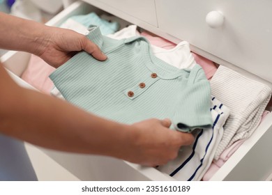 hand of mother taking baby clothes from open cabinet drawer - Powered by Shutterstock