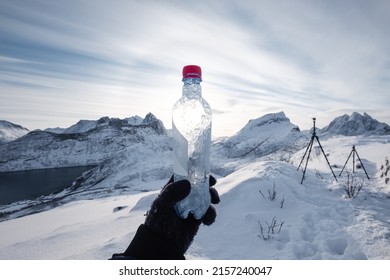 Hand Of Mountaineer Holding Water Bottle On Snow Covered Mountain Peak In The Morning