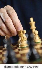 Hand Moving A Knight Chess Piece On Wooden Chessboard