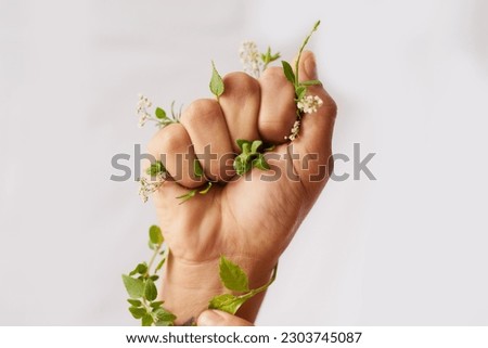 Hand, nature growth and holding fist for eco warrior, fight and revolution for sustainability protest. White background, studio and person with leaf and green plant in hands for environment rally