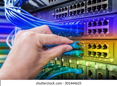 hand with network cables connected to servers in a datacenter