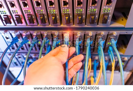 hand with network cables connected to servers in datacenter