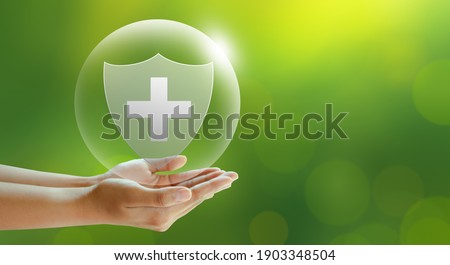 Hand offer medical shield on green background. Family life insurance, Medical care insurance, and Business healthy concepts. 