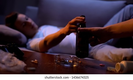 Hand Offering Addicted Young Male Bottle Of Beer, Detrimental Alcohol Abuse