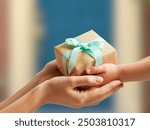 A hand offers a small, beautifully wrapped gift to another hand, symbolizing generosity, kindness, and the spirit of giving,International Day of Charity