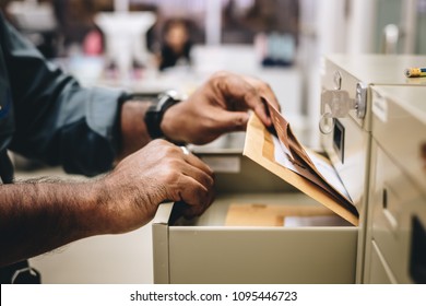 a hand of office employee choose and pick a folder of document paper from opened office's steel drawer