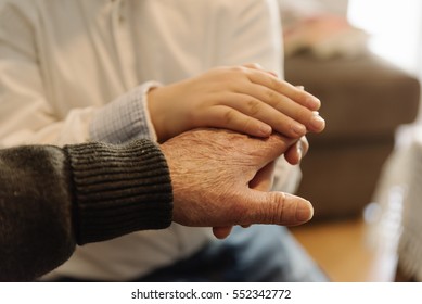 Hand Of Old Person Holding Hand Of Kid. Old Age Concept.