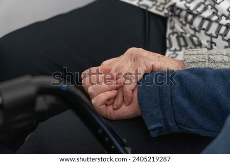 Hand of an older woman holding the hand of another woman