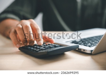 Hand on calculators, aiming for home refinance. Wooden house model, buy or rent note on desk. Concept of saving to buy property, wise mortgage payment. Tax, credit analysis for financial benefit. Stockfoto © 