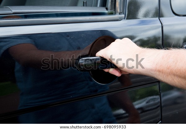 A hand on the door\
handle of a car