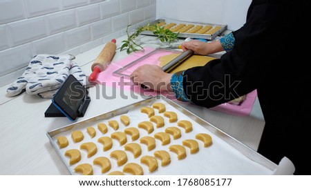 Hand on frame; someone is making a cake while looking at a tutorial on a cell phone.