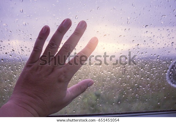 hand on glass of car in\
rainy day