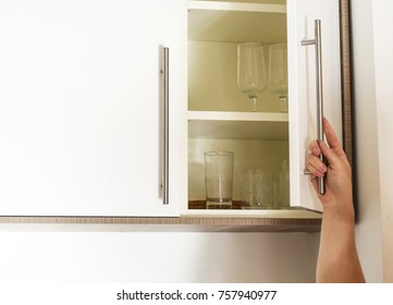 Hand On Handle Opening Cabinet Door In Kitchen