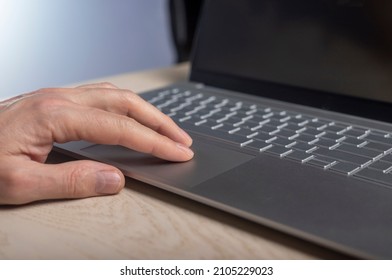 Hand on laptop touchpad, tapping and scrolling with fingers close up.