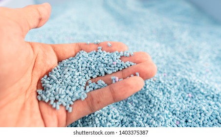 Hand On Large Pile Of Blue Plastic Granules In Temporary Storage Of Production Line At Recycle Factory, Masterbatch Dye Polymer Plastics Resin Pellet Background,  Injection Molding Process Lab