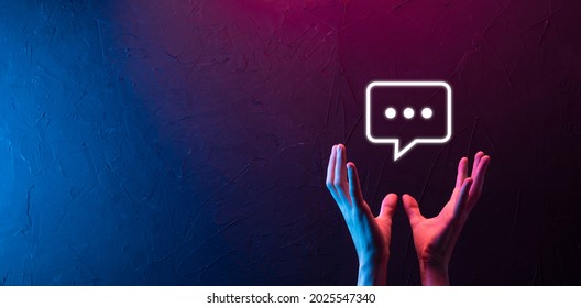 Hand on neon background holding a message icon, bubble talk notification sign in his hands. Chat icon, sms icon, comments icon, speech bubbles. - Shutterstock ID 2025547340