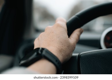 hand on the steering wheel of a car in traffic for safe and controlled driving on city roads - Powered by Shutterstock