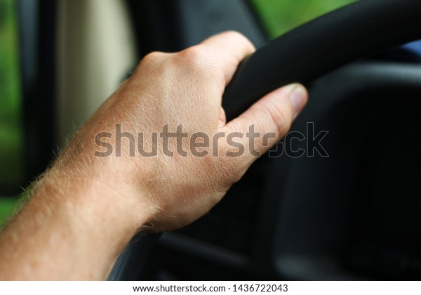 The hand\
on the steering wheel of the car\
close-up